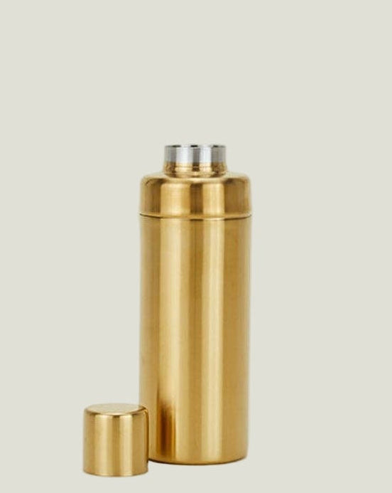 Gold thermos bottle on a beige background