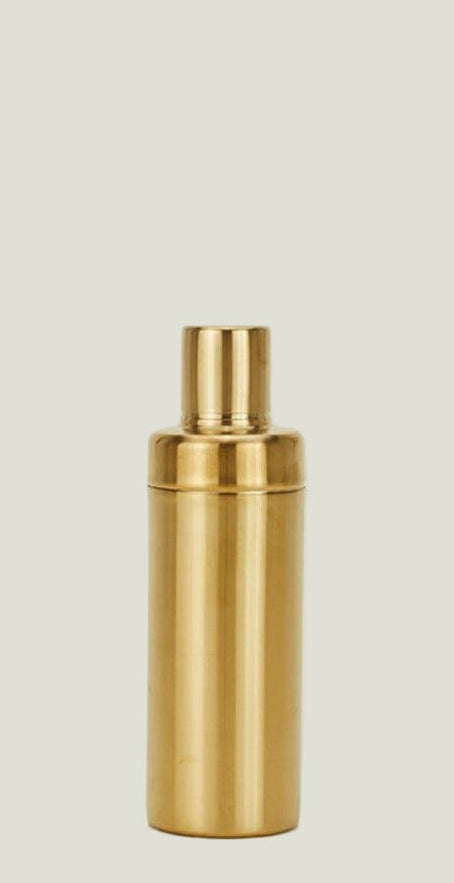 Gold-colored cocktail shaker on a beige background