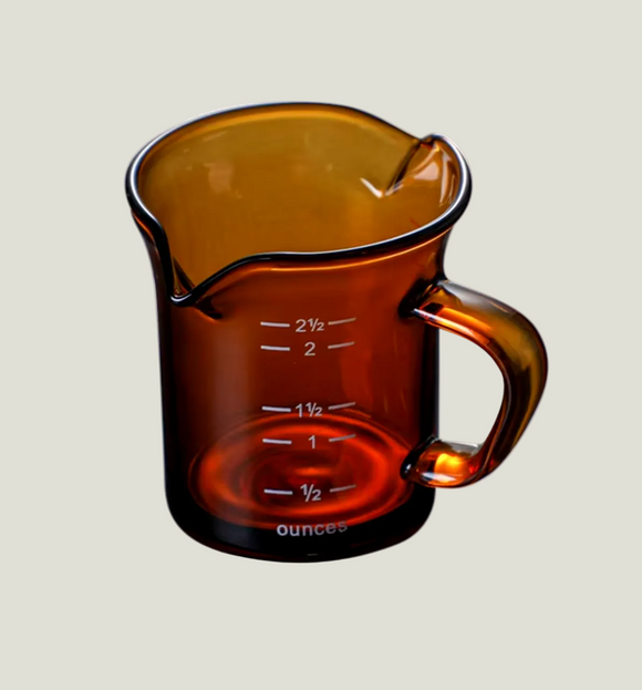 Brown glass measuring cup with measurement markings on a white background