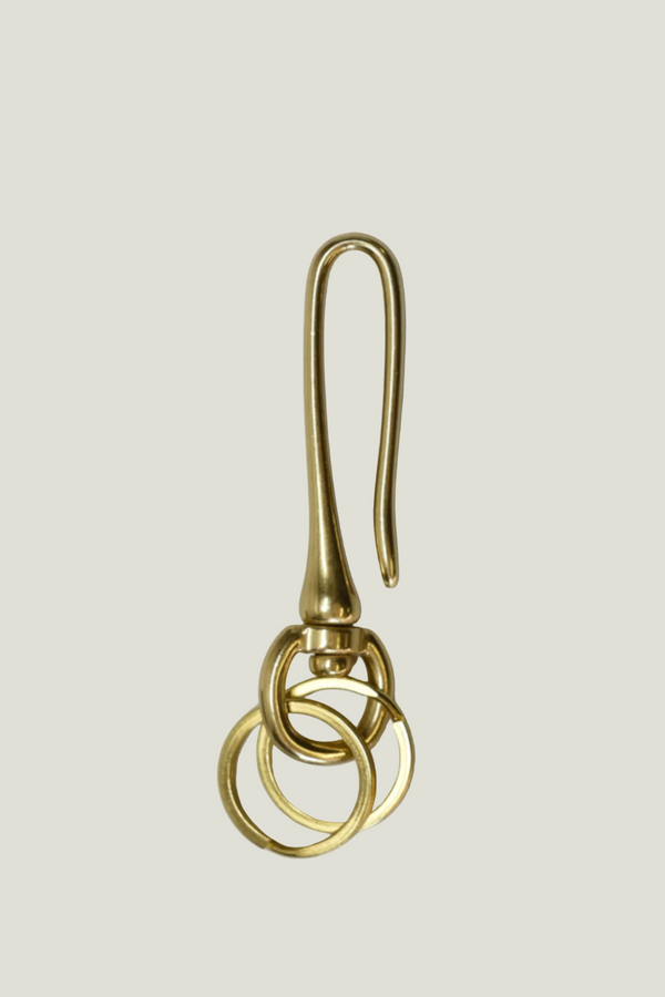 Gold earring with three interlocking rings on a beige background