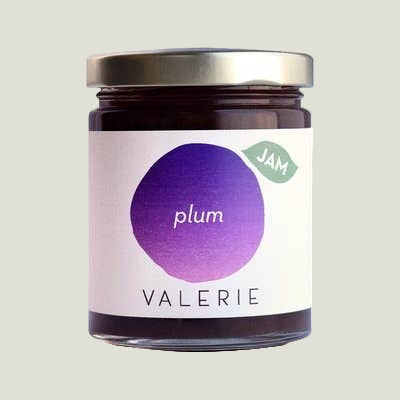 Jar of plum jam with a purple label on a white background
