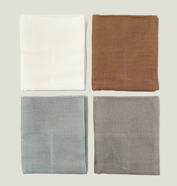 Four folded fabric swatches in white, brown, blue, and gray on a light gray background