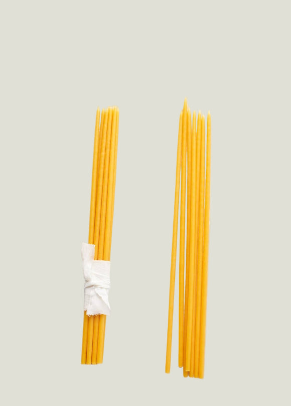 Two bundles of yellow spaghetti noodles on a textured white surface