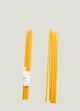 Two bundles of yellow spaghetti noodles on a textured white surface