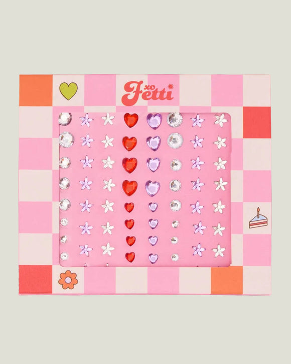 Pink and orange checkered sheet with decorative stickers featuring hearts, flowers, and other shapes on a light gray background.