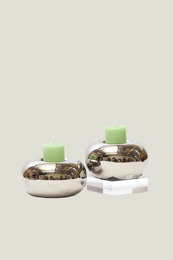 Two silver candle holders with green candles on a white background