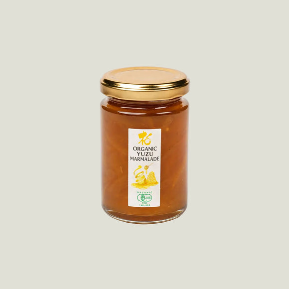 Jar of organic yuzu marmalade with a gold lid on a white background