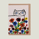 Card with a line drawing of a cat's face behind colorful flowers on a light pink background.