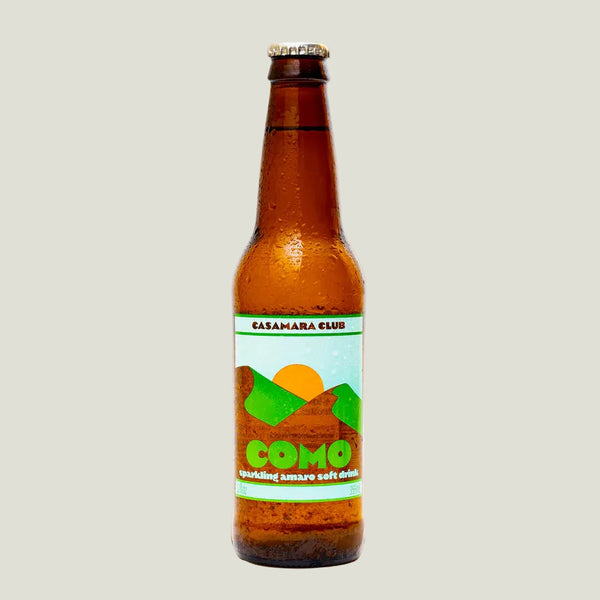 Brown glass bottle with a colorful label on a beige background