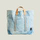 Light blue denim tote bag with brown leather straps on a white background