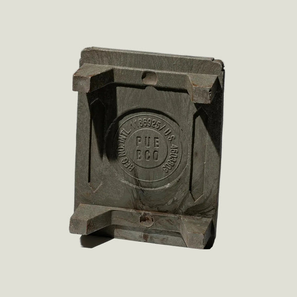 Metallic square object with 'PUE BCO' branding on a white background