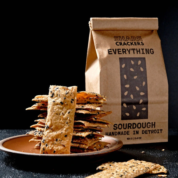 Bag of Sourdough Crackers with a plate of crackers on a dark background